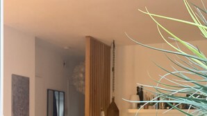 Ein modernes Wohnzimmer mit einer Couch, einem Sessel mit Kuhfellkissen, einer Stehlampe und einer Blumentopf-Pflanze.