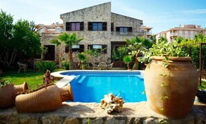 A stone building with a swimming pool, surrounded by greenery and potted plants. - VILLA HERMOSA-  Stone house with private pool in Las Palmeras, 4 bedrooms. VERY POPULAR - Free Wifi (Llucmajor)