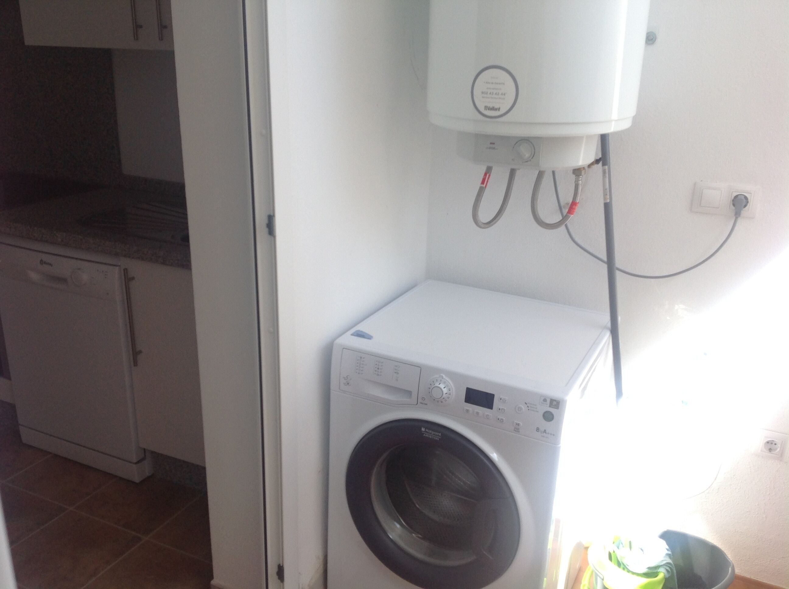 Een kleine wasruimte met een voorlader wasmachine en een wandradiator.