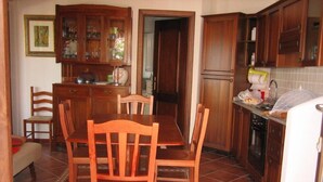A kitchen with wooden cabinets, a dining table with chairs, and a refrigerator.