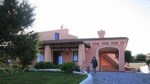 A house with a stone driveway, a covered entrance, and a satellite dish on the roof.
