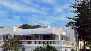 A modern building with a white facade, large windows, and a balcony.