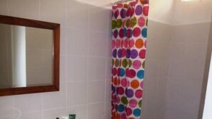 A bathroom with a white sink, mirror, and a shower with a colorful polka dot curtain.