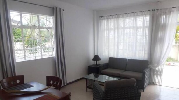 A living room with a sofa, a coffee table, a dining table with chairs, and a lamp.