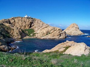Un paysage côtier caractérisé par un terrain rocheux et la présence d’un phare.