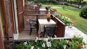 Eine Terrasse mit Tisch und Stühlen, umgeben von einem Holzzaun und Kübelpflanzen.