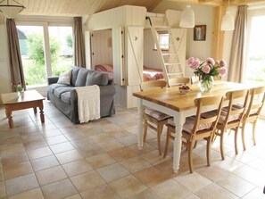 A cozy room with a sofa, a dining table with chairs, a ladder, and a view of greenery outside. - Beautiful, country style cottage near the windmill, polder and windmill view (Alphen aan den Rijn)