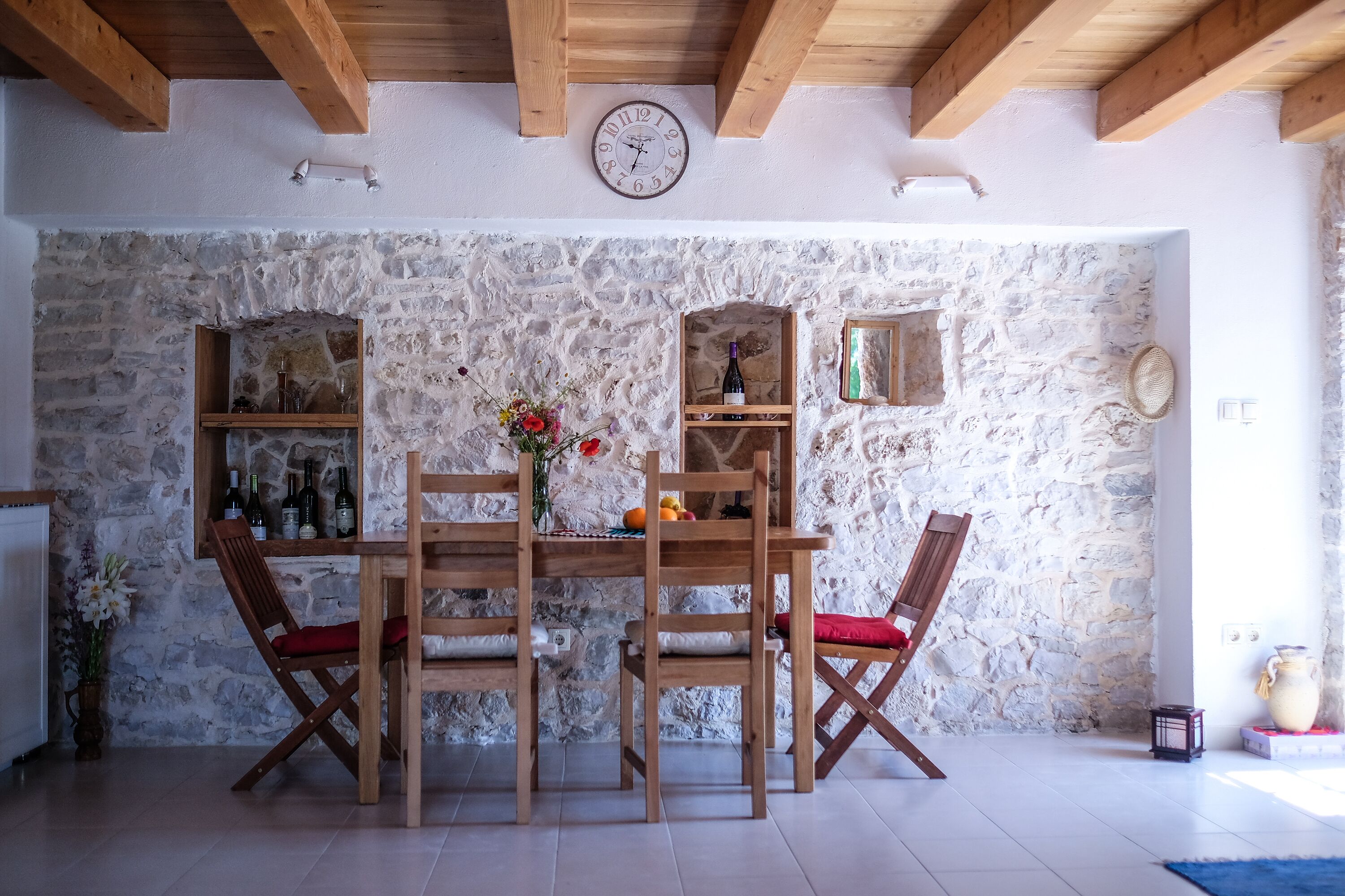 Un coin repas avec un mur en pierre, des meubles en bois et une horloge.