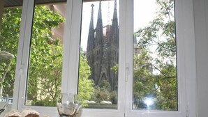 A dining table with a view of a cathedral through a window. - Apartment overlooking the Sagrada Familia, completely renovated and bright (Barcelona)