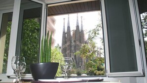 A dining area with a table set for two, a window with a view of a gothic-style building. - Apartment overlooking the Sagrada Familia, completely renovated and bright (Barcelona)