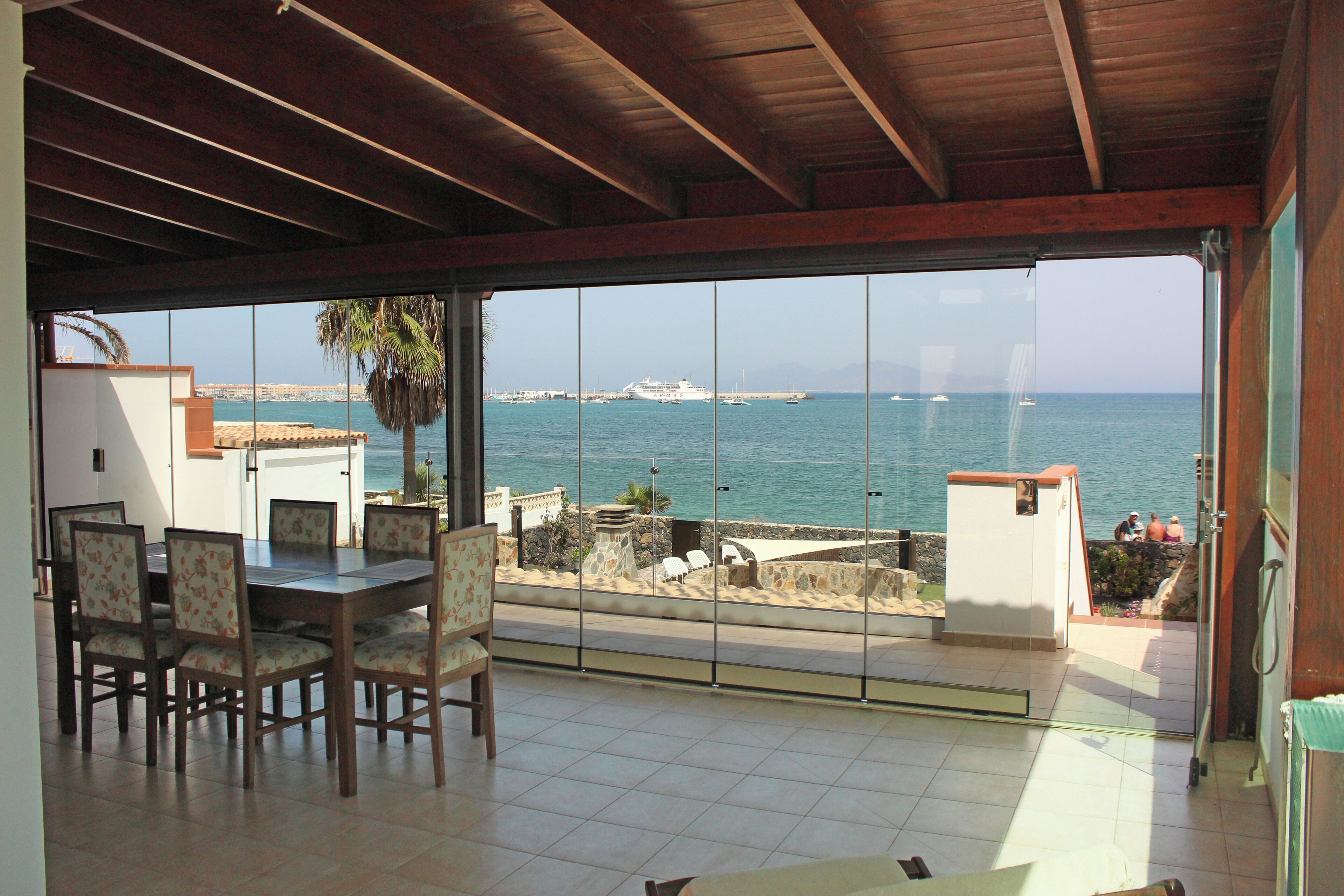 Un espace repas offrant une vue sur la mer et sur un navire au loin.