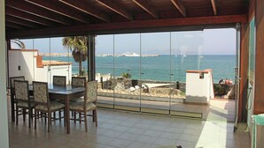 A dining area with a view of the sea and a ship in the distance. - Private, independent villa on the front line, terrace and tranquility (Corralejo)