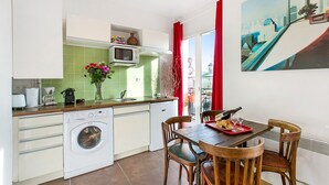 Une cuisine compacte équipée d’un lave-linge, d’un four à micro-ondes et d’un coin repas avec une table et des chaises.