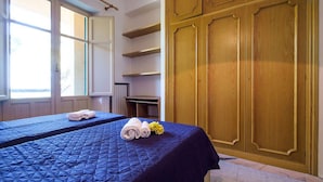 Habitación de hotel con dos camas, un armario de madera grande y una ventana con vistas.