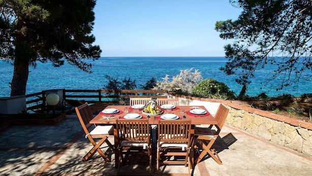 Un área de comedor al aire libre con una mesa dispuesta para cuatro personas, con vista al mar.