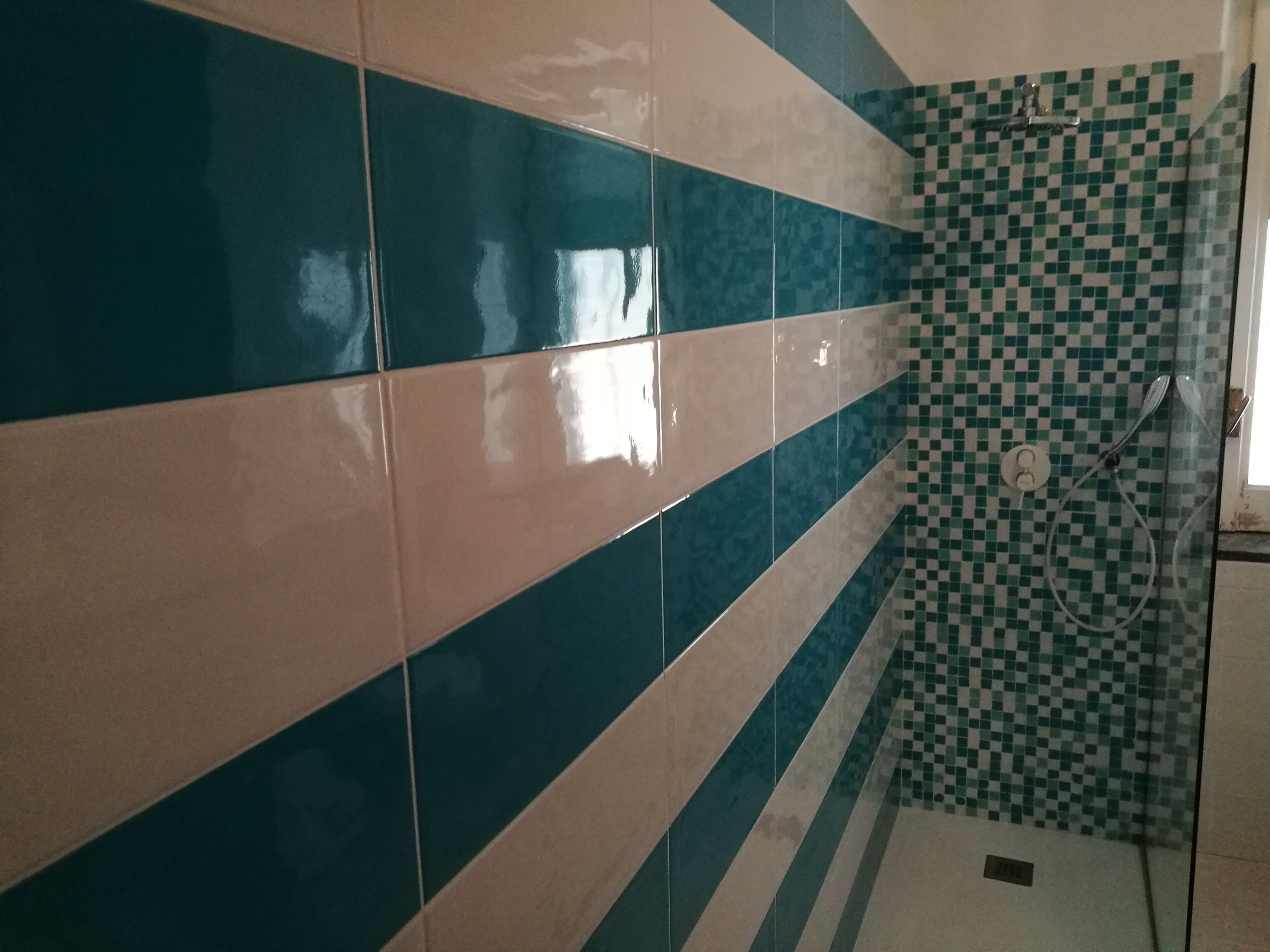 Ein Badezimmer mit einer gefliesten Wand in Blau- und Beigetönen.