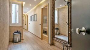 A hallway with a wooden floor, a large mirror, and a door with a metal handle. - Discover Comfort & Culture in the Heart of Barcelona! (Barcelona)