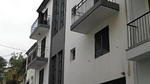 En flervåningsbostadsbyggnad med balkonger och ett garage.