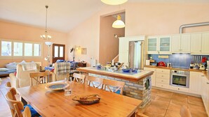 Una cocina amplia con una isla central, un comedor con mesa de madera y una sala de estar acogedora con sofá y sillones.