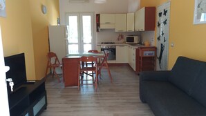 A compact living space with a dining area, kitchenette, and a sofa.