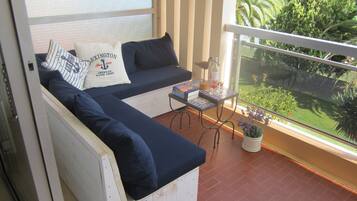 Een balkon met een bank, een kleine tafel en een potplant.