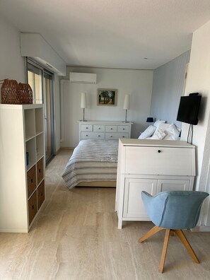 Een slaapkamer met een bed, een dressoir, een stoel, een televisie en een kledingkast.