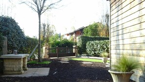 Un jardin aménagé avec un chemin pavé, un banc en pierre et une plante en pot.