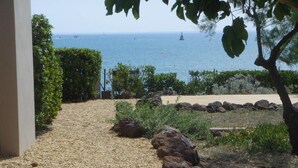 Un sentier de gravier mène à une plage d’où l’on a une vue sur la mer et les bateaux.