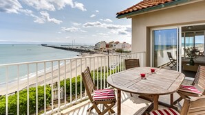 Un balcon avec vue sur la mer, une table avec des chaises et une rambarde.
