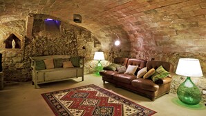 Una habitación acogedora con pared de piedra, un banco de madera, un sofá de cuero y dos lámparas.