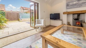 Una sala moderna con una mesa de centro de vidrio, un sillón blanco, un televisor y una chimenea.