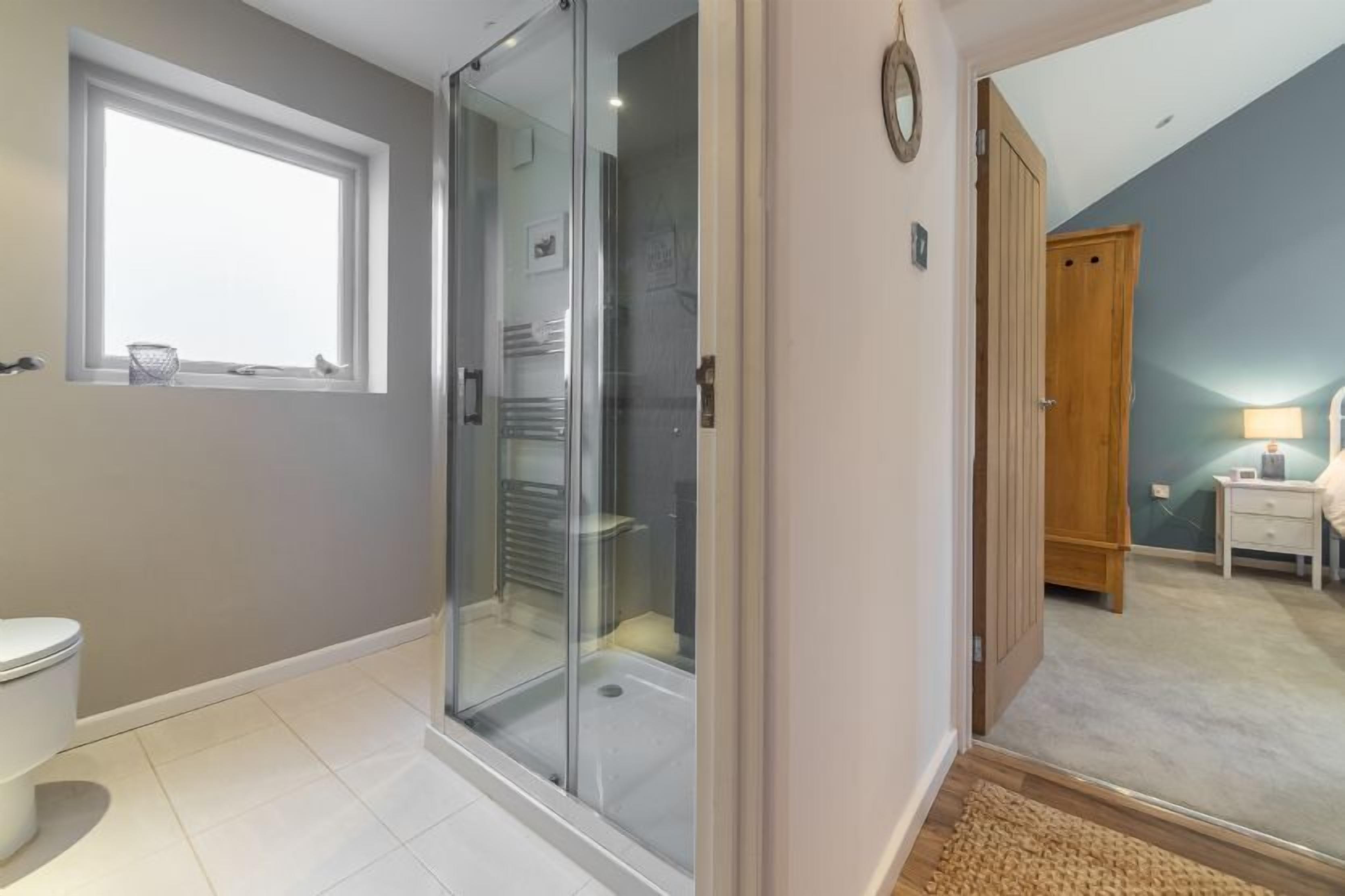 Une salle de bain moderne avec une douche à parois de verre, des toilettes et une fenêtre.
