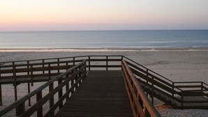 A wooden boardwalk leading to a beach with a clear view of the ocean.