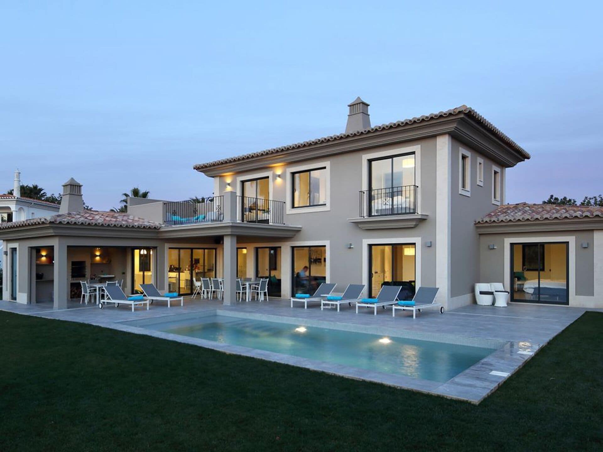 A two-story house with a swimming pool, outdoor seating, and a balcony.