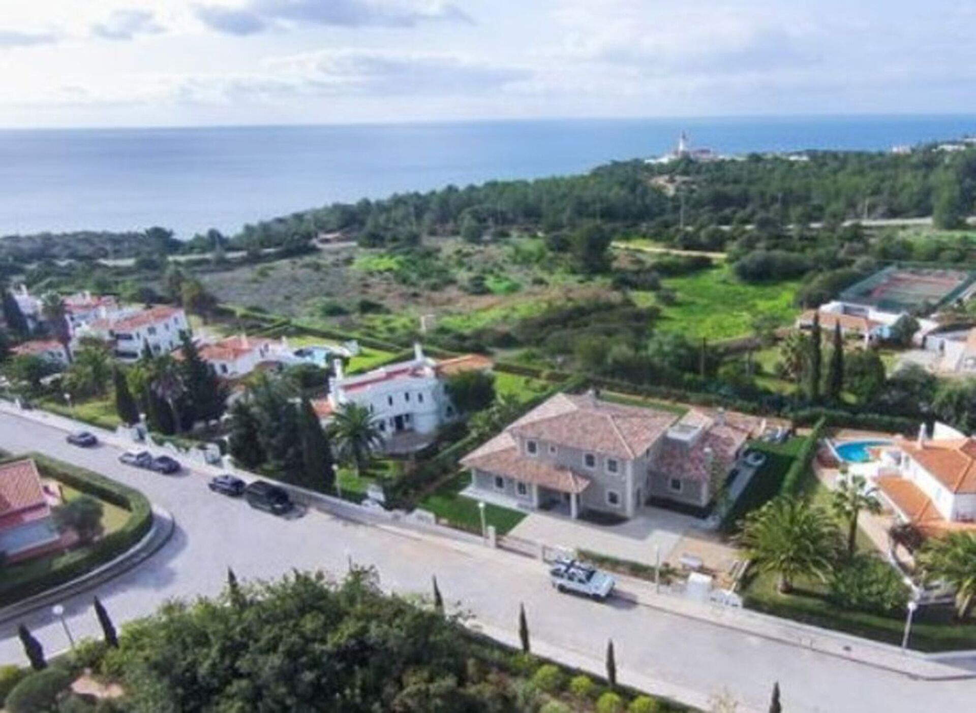 A coastal residential area with houses, a road, and a view of the sea.