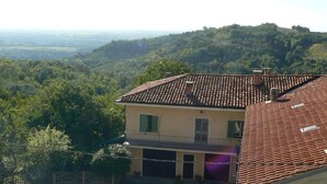 A two-story building with a tiled roof, a balcony, and a view of a hilly landscape. - Villa Elma - Cozy Apartment In The Langhe (Cigliè)