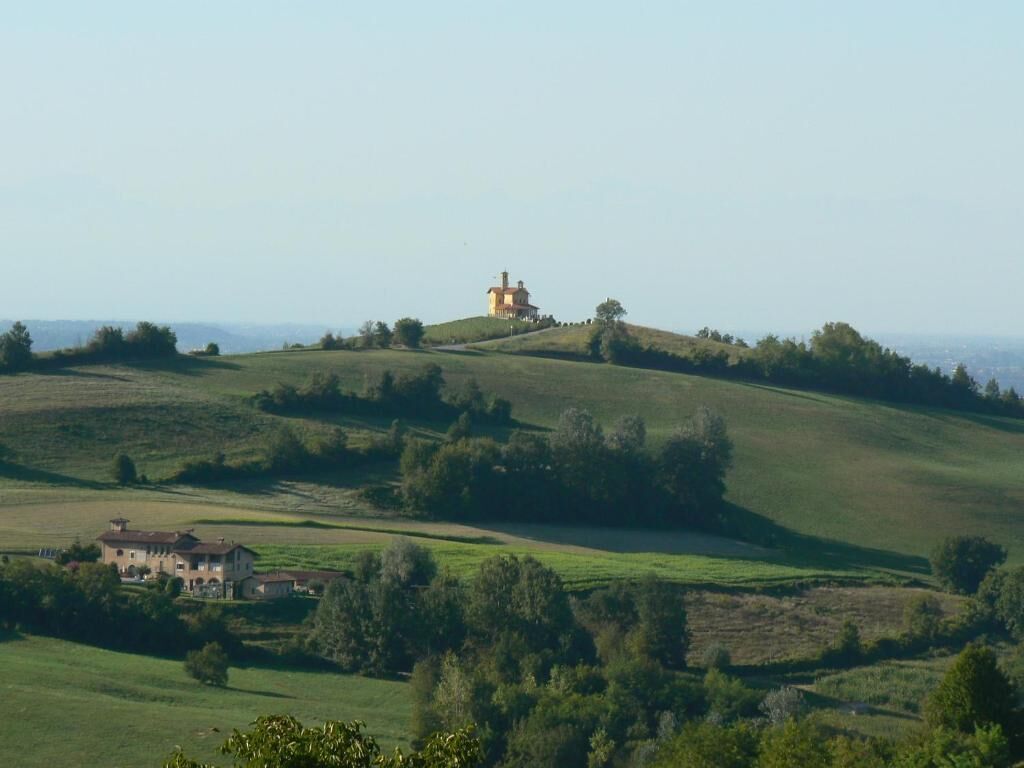 A large estate with a prominent house on a hill, surrounded by rolling green fields and trees.
