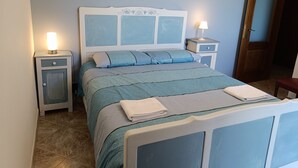 A bedroom with a bed, two bedside tables, a nightstand, and a door. - Villa Elma - Cozy Apartment In The Langhe (Cigliè)