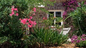 A stone building with a tiled roof, surrounded by lush greenery and flowering plants. - Quiet Villa in Private Domain, Seaview, Heated Pool, BBQ, Walk to the Beach (Roquebrune-Sur-Argens)
