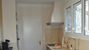 A compact kitchen with a white door, a sink, and a countertop with a kettle. - Quiet Villa in Private Domain, Seaview, Heated Pool, BBQ, Walk to the Beach (Roquebrune-Sur-Argens)