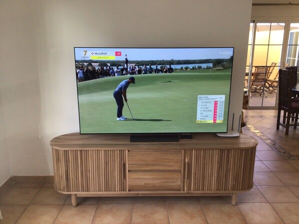 A television displaying a golf tournament on a wooden cabinet. - 'Villa Jasmine' Fabulous Luxury Property In Unequaled Location Golf & Sea Views (Fuerteventura)