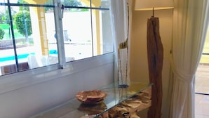 Una mesa con cubierta de vidrio y base de madera natural, un tazón sobre la mesa y una lámpara a un lado.