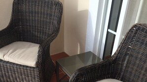 Two wicker chairs with cushions on a tiled patio.
