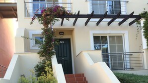A building with a black door labeled N3, a set of stairs leading to a balcony, and a hanging flower basket.