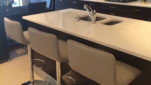 A modern kitchen with dark cabinets, a white countertop, and a central island with bar stools.