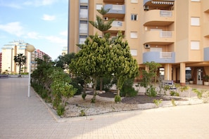 Un edificio residencial de varios pisos con balcones y un jardín ajardinado.