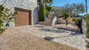 A stone building with a wooden garage door, a stone staircase, and a gravel driveway.