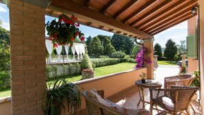 A covered patio with wicker furniture, a view of a garden, and a brick wall. - Il Poggiolo, house between country and sea! (Montemagno)