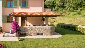 A two-story house with a stone facade, a tiled roof, and a small porch with outdoor seating. - Il Poggiolo, house between country and sea! (Montemagno)