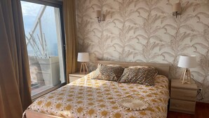 Una camera da letto con un letto grande, due comodini con lampade, una finestra con tende e carta da parati decorata.